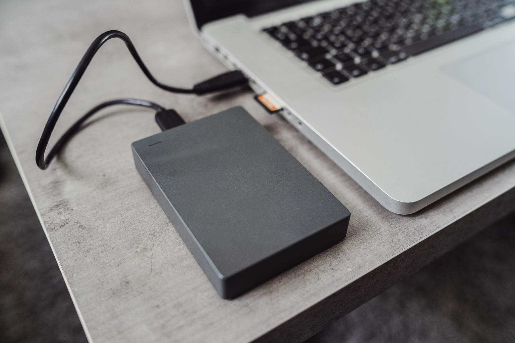 A portable external drive connected to a laptop, ideal for portable workspace software.