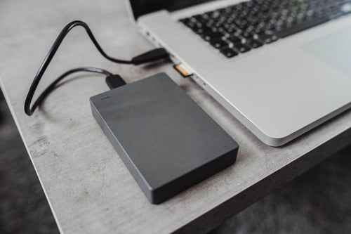A portable external drive connected to a laptop, ideal for portable workspace software.